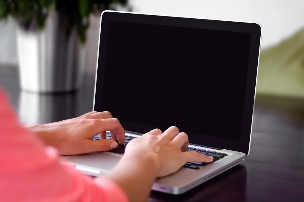 Mains qui tapent un message sur le clavier d'un ordinateur portable