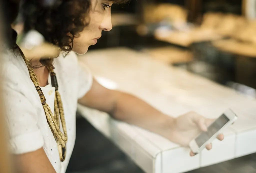 Femme attablée qui relit un message sur son téléphone avant de l'envoyer