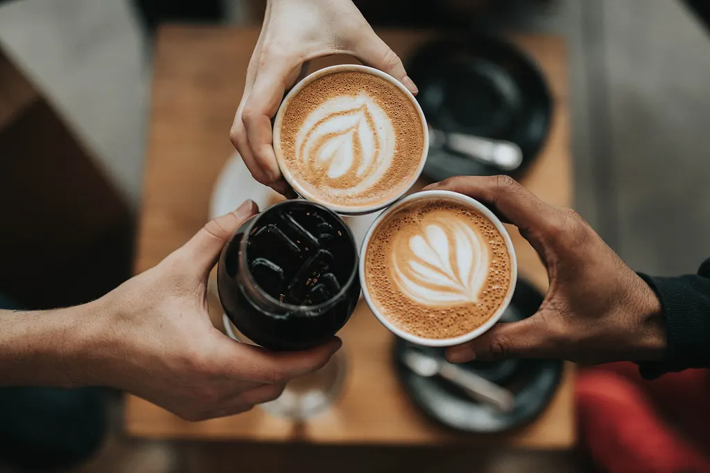 Deux tasses de café qui trinquent au-dessus d'une table en bois