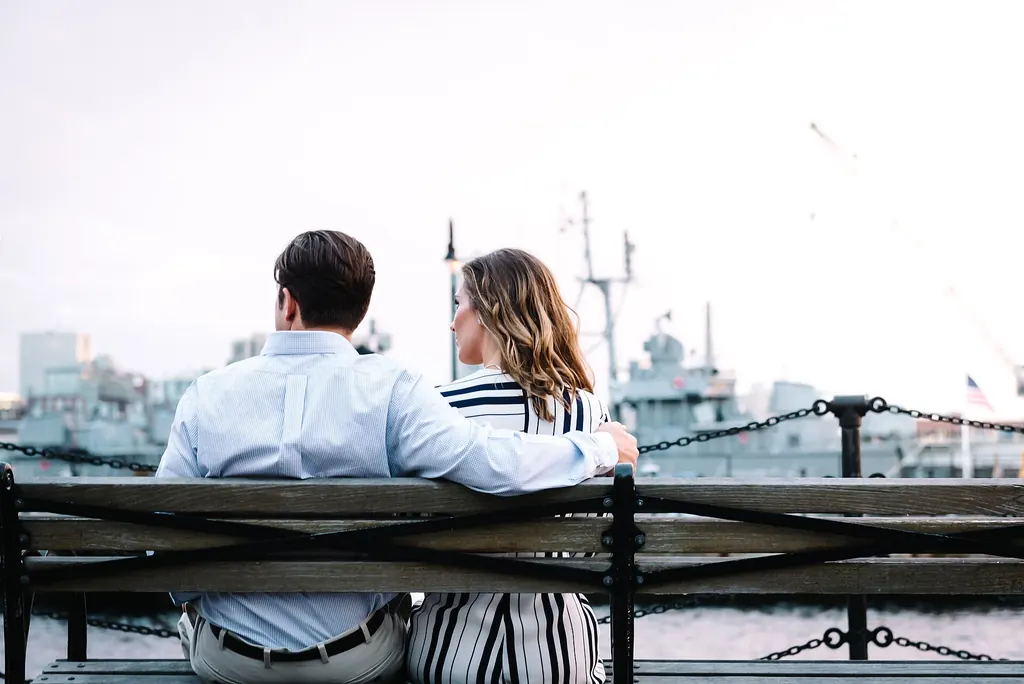 Un homme et une femme assis côte à côte sur un banc, face au port