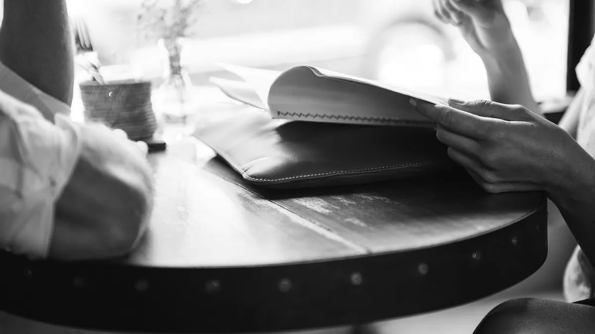 Deux personnes attablées face à face dans un café, en noir et blanc
