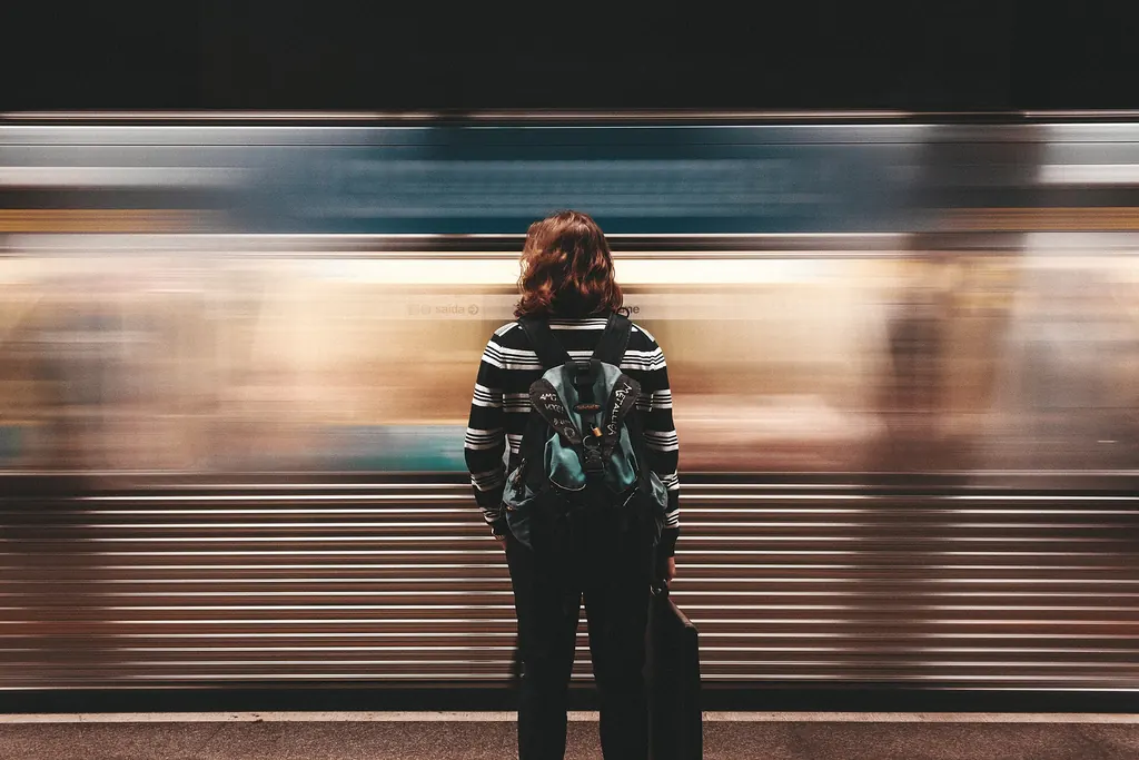 Personne vue de dos sur un quai pendant qu'un métro passe en trombe
