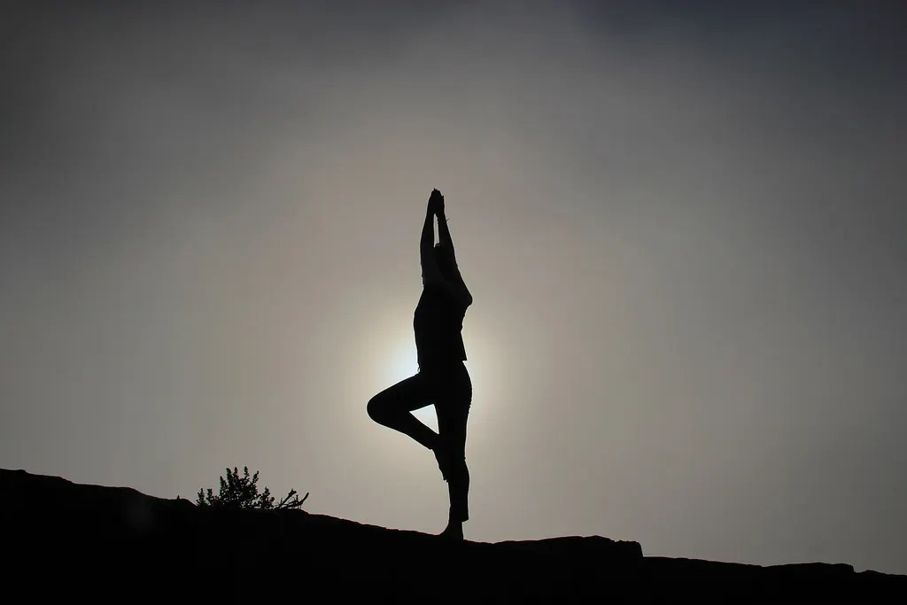 Silhouette en posture d'équilibre sur une colline, dans la brume