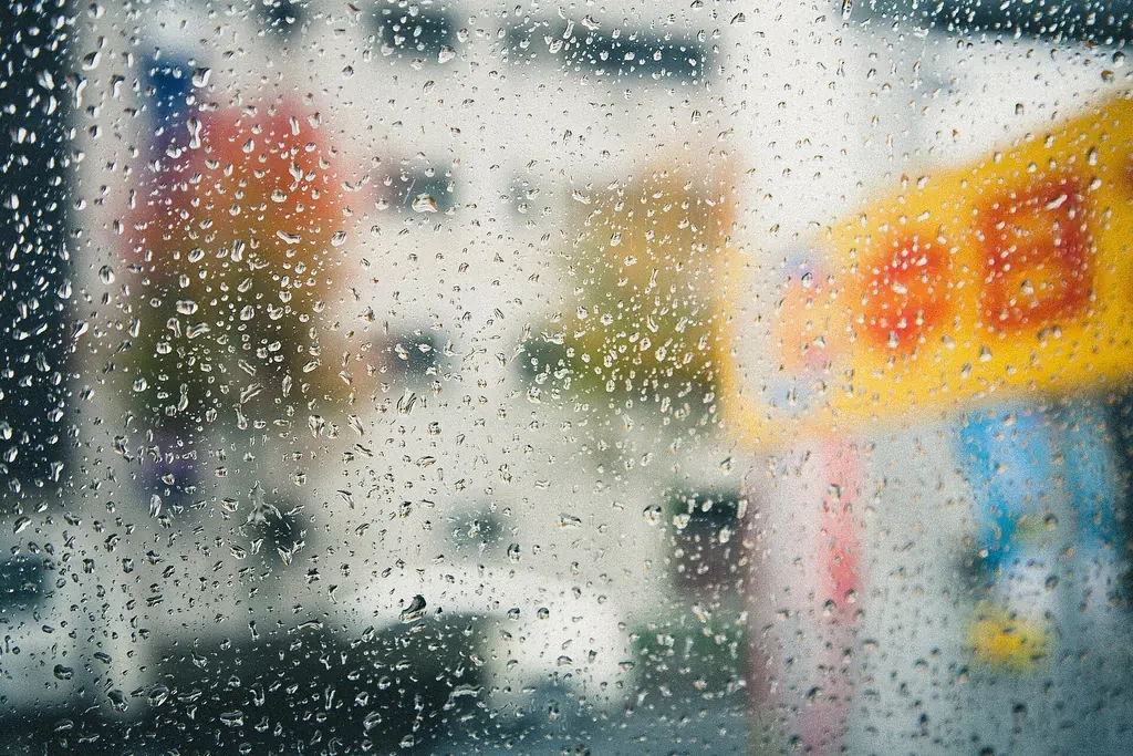Gouttes de pluie sur une vitre, la rue floue en arrière-plan