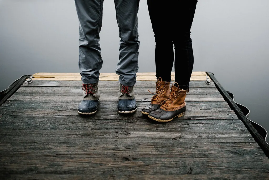 Deux paires de bottes face à face sur un ponton en bois, à une distance respectueuse