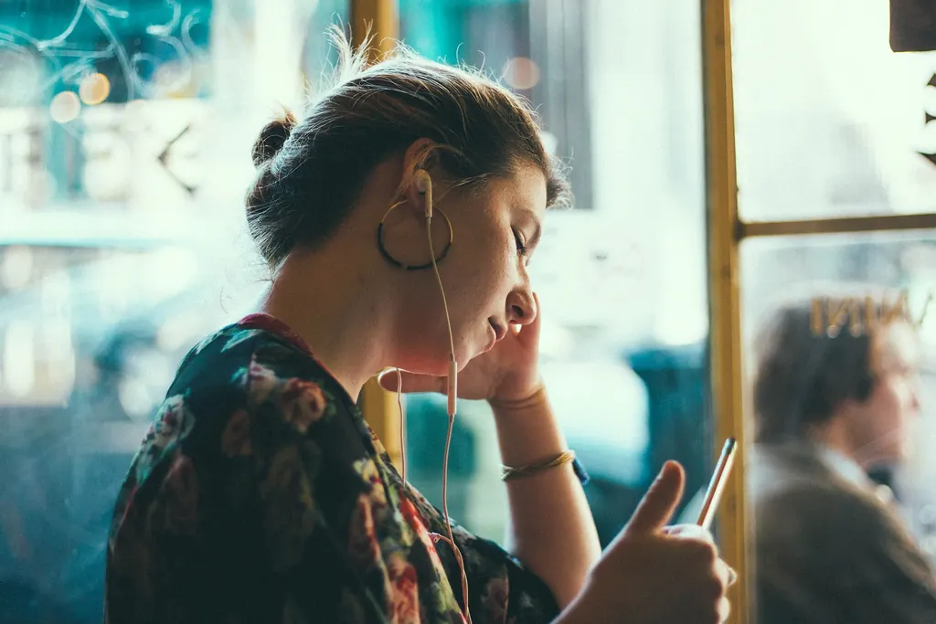 Femme avec des écouteurs qui écoute un message sur son téléphone