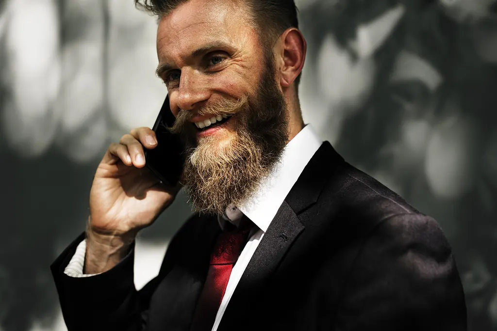 Homme barbu au large sourire pendant un appel téléphonique